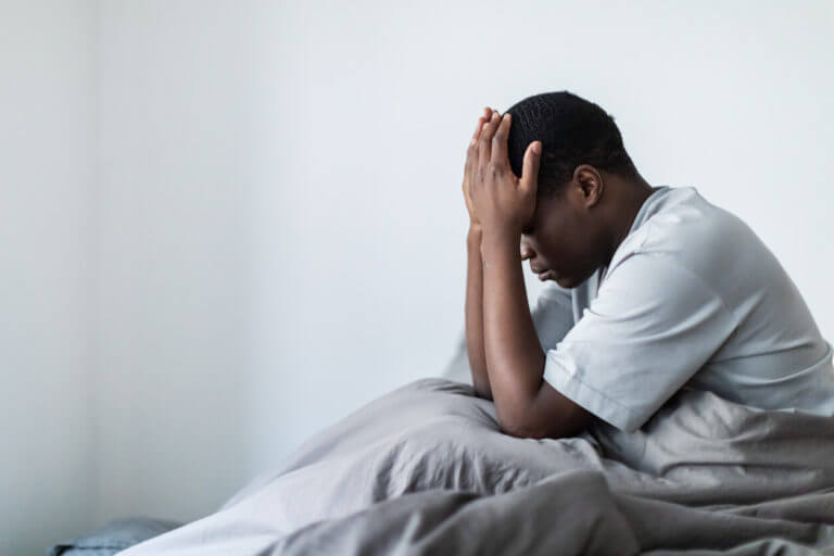 Depressed man sitting in bed worrying about his erectile dysfunction